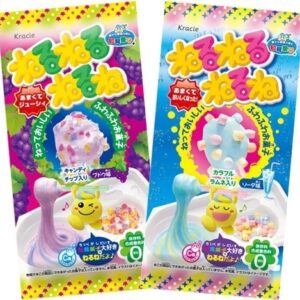 Twee verpakkingen van Popin' Cookin' Neru Neru Nerune DIY snoep kits naast elkaar. Links de paarse verpakking met druivensmaak, rechts de blauwe verpakking met frisdranksmaak, beide tonen het gemaakte schuimsnoep en de ingrediënten